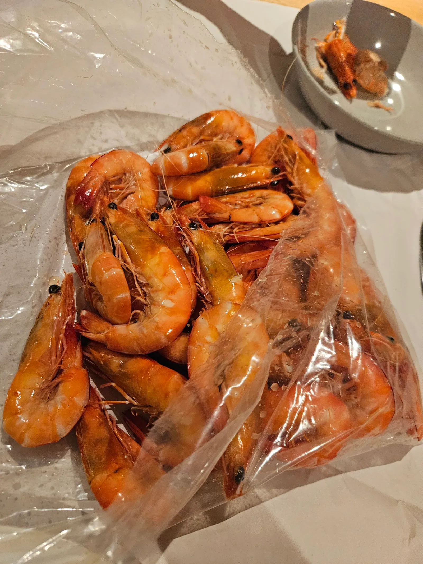 Bag of cooked prawns on white butcher paper with dipping sauce